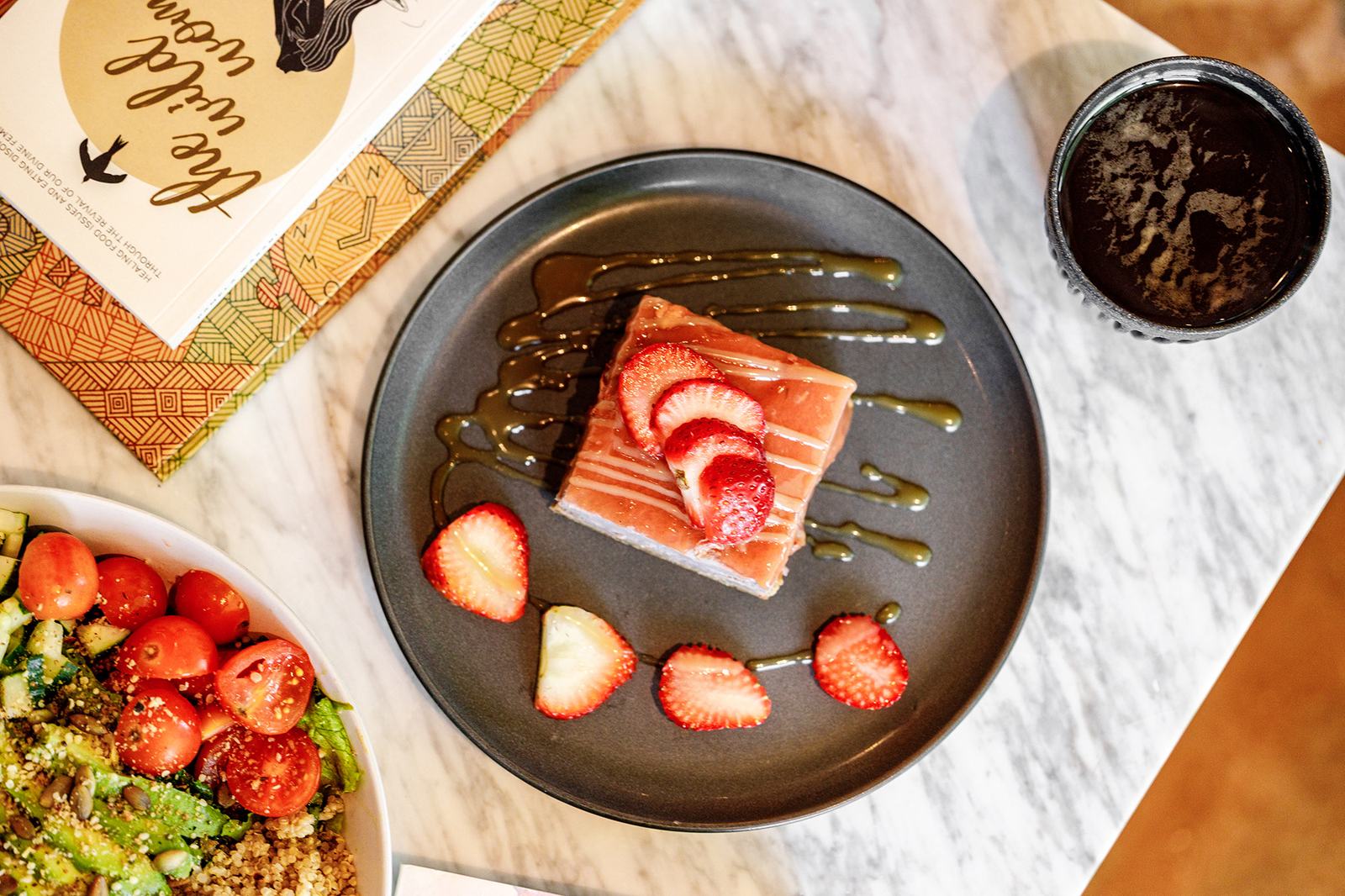 A slice of crepe cake topped with fresh strawberries and a green dessert sauce.